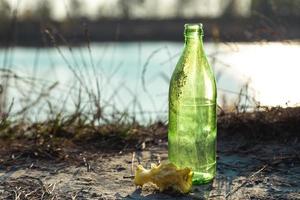 Botella de vidrio sucia en el bosque junto a un trozo de manzana foto