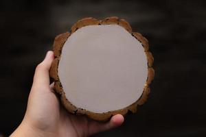 Mano de mujer sosteniendo una pieza circular vacía de sección de madera foto
