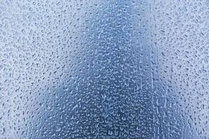 Raindrops on textured blue glass background photo