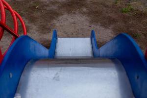 Children's slide with blue sides and a shiny metal surface photo