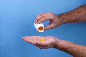 Man holds yellow medication capsules of omega photo
