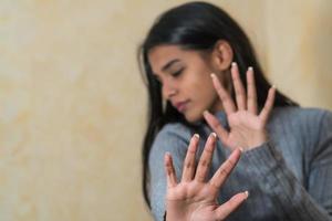 Woman says stop Self defence young Indian woman covering her face with hand photo