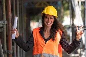 dando el signo v en el sitio de construcción foto