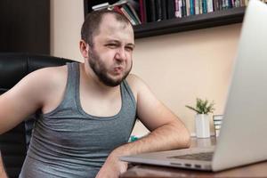 Young bearded guy leisurely using laptop photo