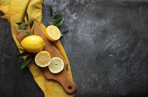 Lemons and green leaves on bright black background photo