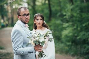 Foto de boda de la novia y el novio en un color rosa grisáceo en la naturaleza en el bosque y las rocas