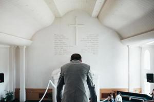 Foto de boda de las emociones de un novio barbudo con gafas en una chaqueta gris en el edificio de la iglesia