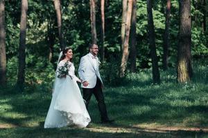 la novia y el novio están caminando por el bosque el día de su boda foto