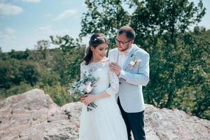 Wedding photo of the bride and groom in a gray pink color on nature in the forest and rocks