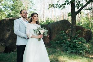 Foto de boda de la novia y el novio en un color gris rosa en la naturaleza en el bosque y las rocas