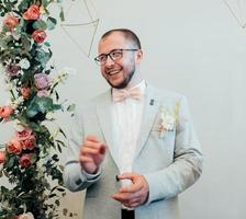 foto de boda de las emociones de un novio barbudo con gafas en una chaqueta gris y estilo rústico