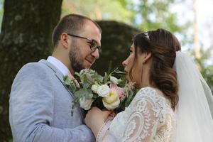 Wedding photo of the bride and groom in a gray pink color on nature in the forest