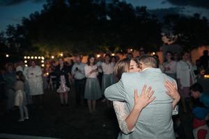 Bride and groom hugging at night on the background of guests at the banquet photo