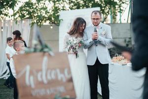 Bride and groom at a wedding party and a wooden easel in the foreground with space for text photo