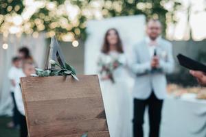 La novia y el novio en una fiesta de bodas y un caballete de madera en primer plano con espacio para texto