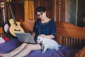 Mujer joven que trabaja en el portátil en casa lindo perro pequeño además de trabajar desde casa foto