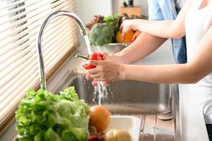 Couple washing vegetable in sink photo