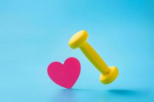 Dumbbell and heart shaped leaf on blue background with copy space