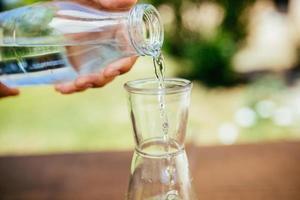 Pouring Water In The Bottle With Cucumber photo