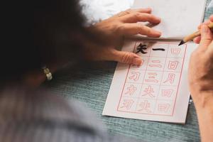 Close up hands of senior woman practices writing calligraphy of traditional Chinese characters photo