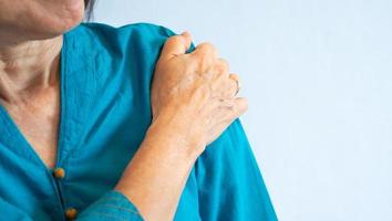 Senior woman getting shoulder pain from frozen shoulder photo