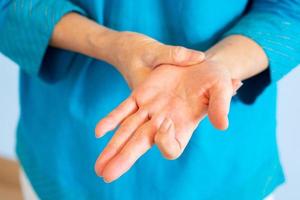 Close up hands of senior woman getting trigger finger from hard working photo