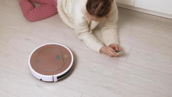 A young woman controls a robot with a vacuum cleaner