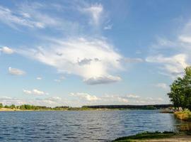 hermoso paisaje soleado de verano con lago verde hierba y cielo con nubes foto