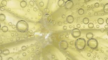 Fotografía macro de una rodaja de limón en una bebida carbonatada con burbujas de gas en aumento video
