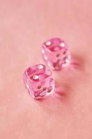 A vibrant monochromatic macro with depth of field about two pink glass gambling dice with two unlucky number two on pink background photo