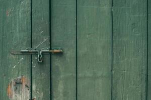 El pestillo de la puerta vieja y oxidada y la cerradura de la puerta de madera verde foto