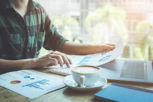 The accountant is pressing the calculator to calculating check the accuracy of the investment budget with using computer laptop and document data to analysis photo