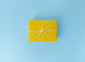 caja de regalo amarilla sobre un fondo azul foto