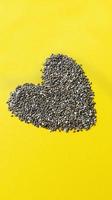 Shape of heart from chia seeds on yellow background Simple flat lay with pastel texture Healthy food concept Stock photo