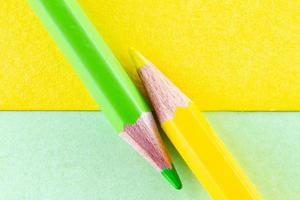 lápices de colores sobre papeles de color amarillo y verde dispuestos en diagonal