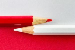 lápices de colores sobre papeles de color rojo y blanco dispuestos horizontalmente