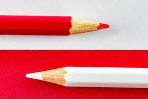 lápices de colores sobre papeles de color rojo y blanco dispuestos horizontalmente