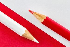 Color pencils on red and white color papers arranged diagonally photo