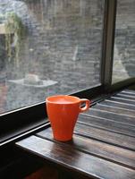 Milk in orange mug on wood table in coffee shop