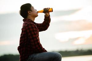 silueta, hombre, tenencia, cerveza, con, ocaso, plano de fondo foto