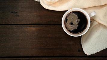 Top view of cup of coffee on a white tablecloth on a wooden table photo