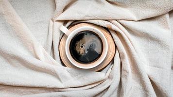 Vista superior de la taza de café sobre un mantel blanco foto