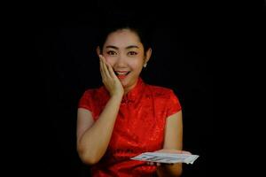 retrato, mujer asiática, vestido rojo, tradicional, cheongsam, tenencia, dinero, 100, dólar, billetes, en, el, fondo negro foto