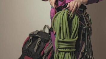 Una mujer vestida con ropa térmica morada recoge el equipo para un viaje de escalada. video