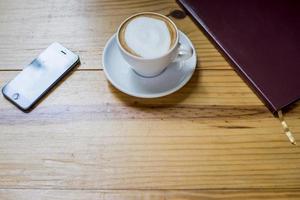 Notebook with cup of coffee on wooden desk photo