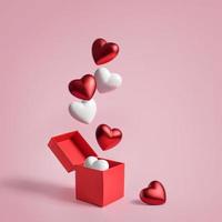 Figurines in the shape of a heart fly out of an open box on a pink background with copy space photo