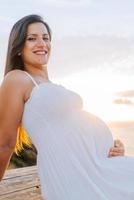 retrato de una mujer embarazada contra un paisaje oceánico foto