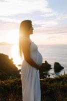 Vista lateral de una mujer embarazada contra un paisaje oceánico foto