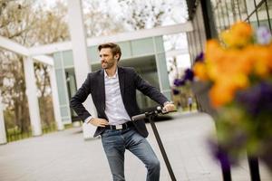 Young business man in a casual clothes standing on electric scooter by an office building on a business meeting photo