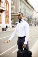 Young African American businessman waitng a taxi on a street
